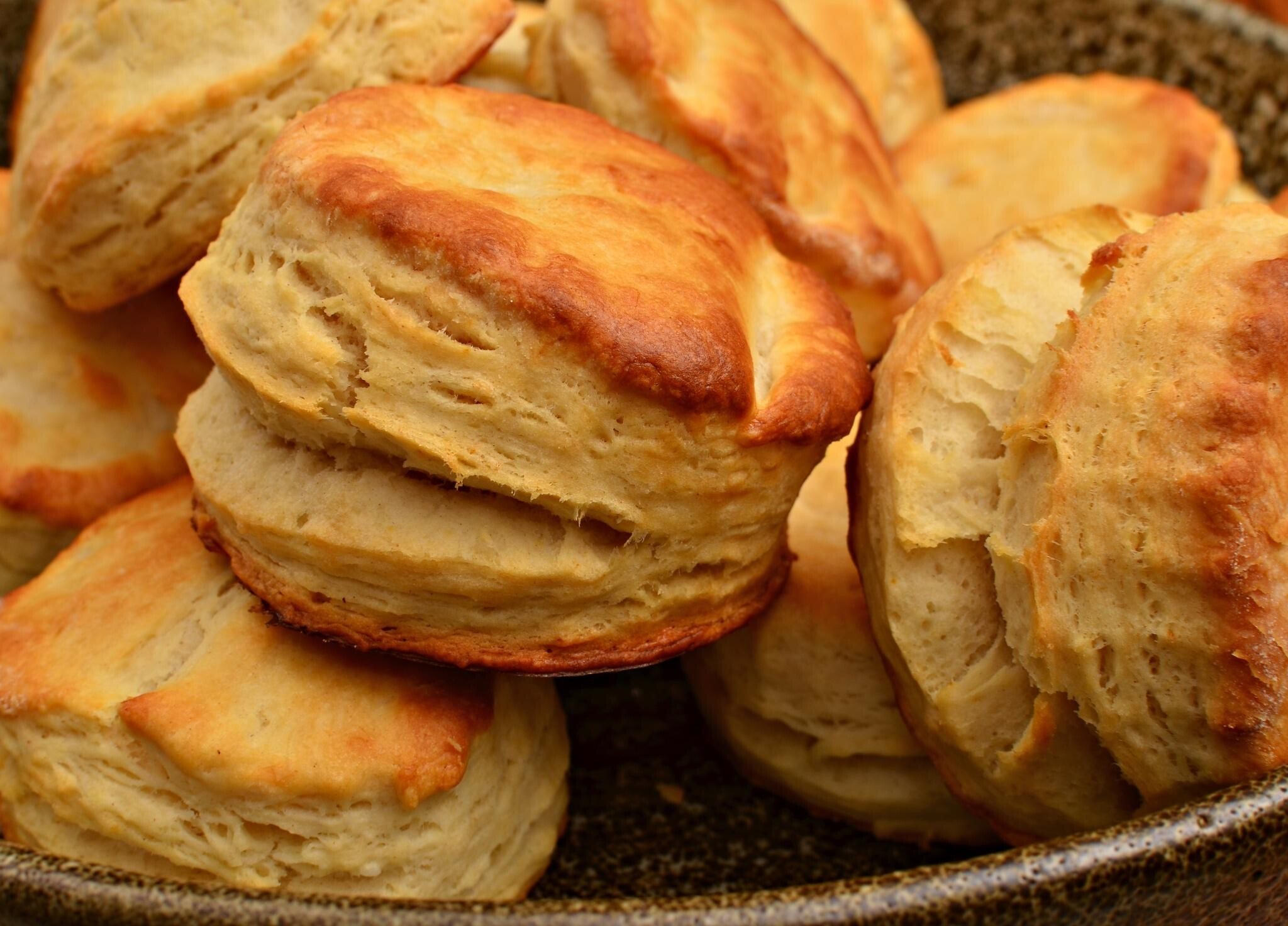 A pile of tall, flaky golden buttermilk biscuits